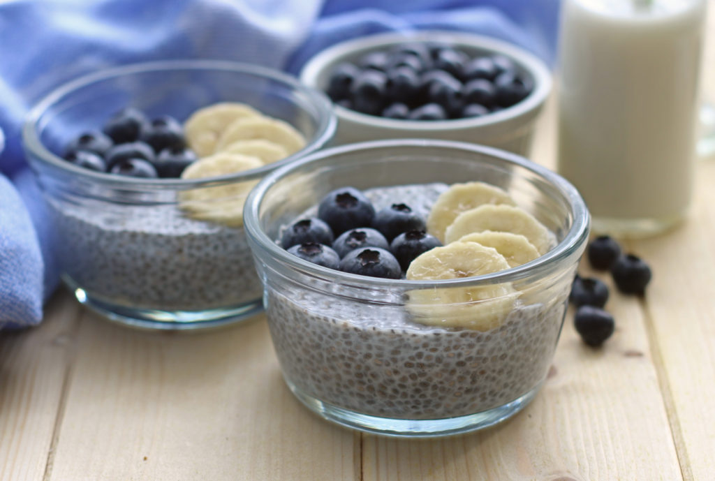 2 Chia Seed Pudding bowls with blueberries and banana on top, plus a white bowl filled with blueberries behind