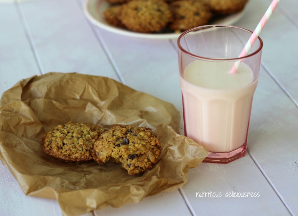 Cookies on a white plate with a glass of milk in a pink glass with a straw