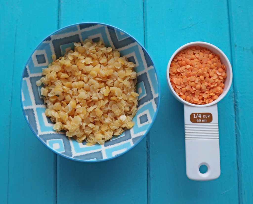 Cooked lentils in a blue bowl with uncooked lentils in another bowl next to it.