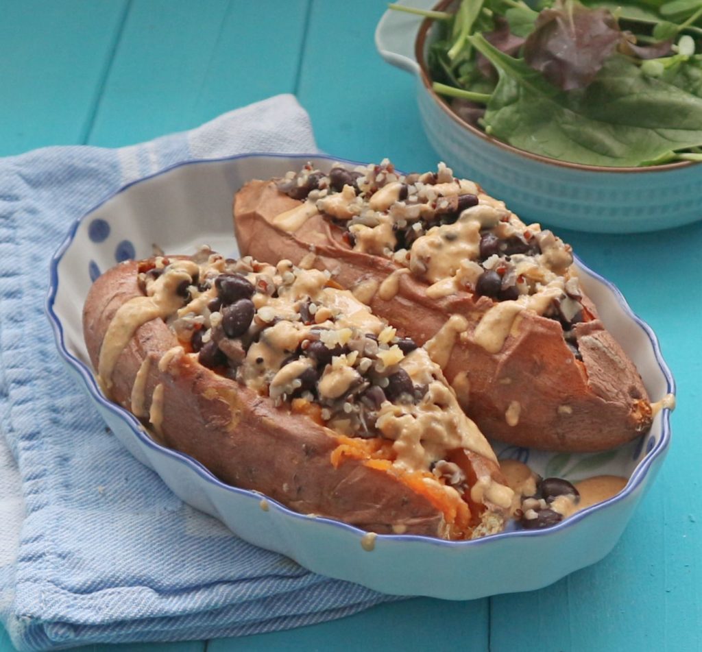 2 roasted Sweet Potatoes with black bean stuffing on a blue wood board.
