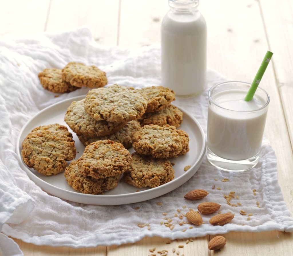Almond Milk Cookies on a white plate with almond milk in a bottle and glass.