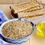 Dukkah in blue bowl with olive oil in glass bowl and bread fingers