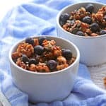 2 white bowls with granola and blueberries on top