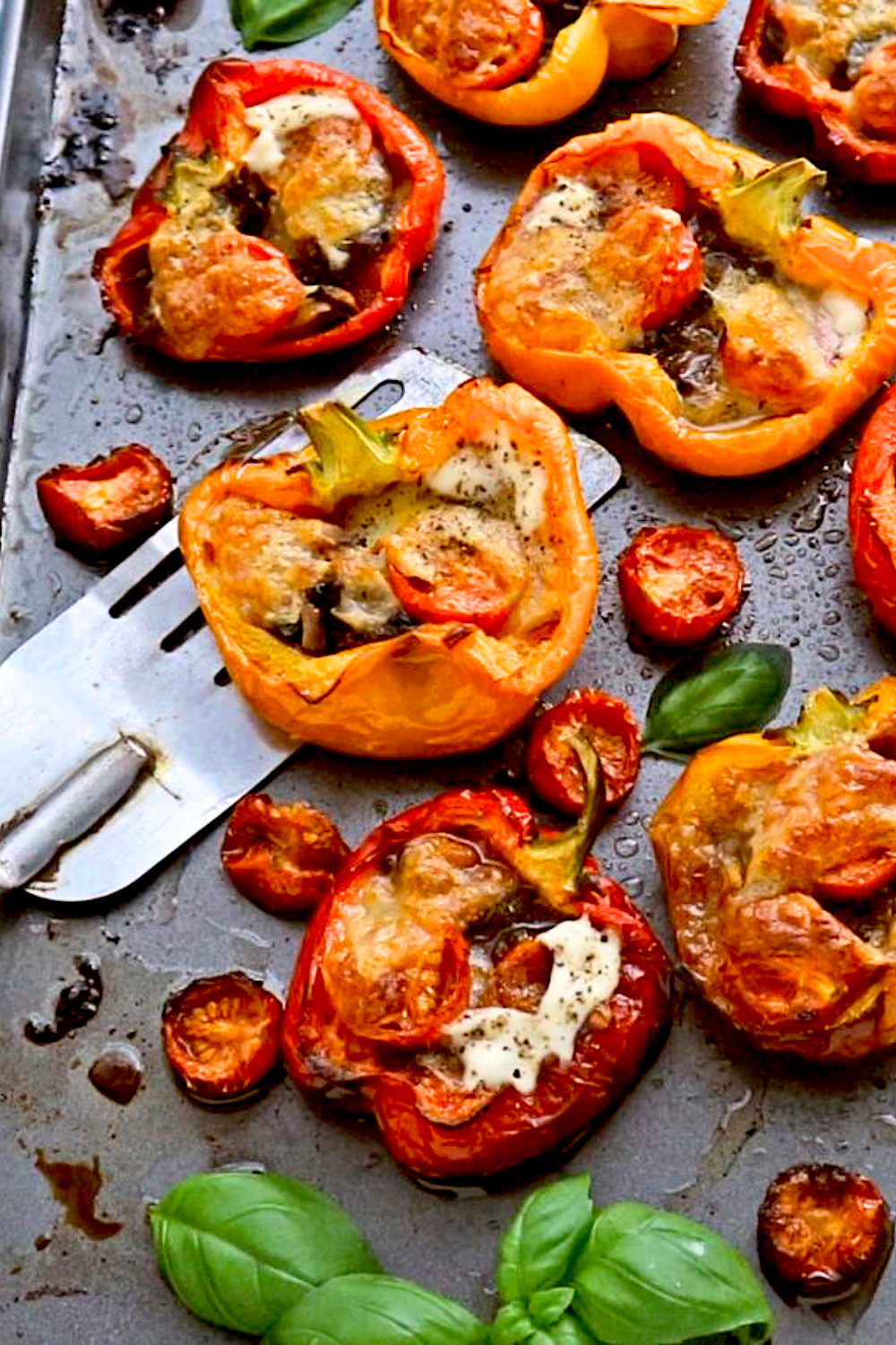 stuffed bell peppers with tomatoes on side of baking sheet with spatula