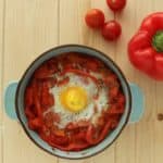 baked egg in tomatoes and bell peppers in blue crock