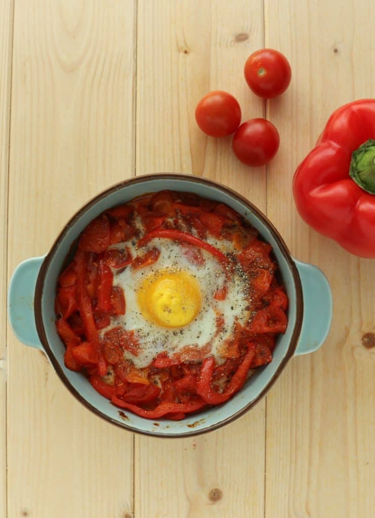 baked egg in tomatoes and bell peppers in blue crock