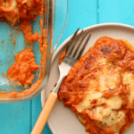 Zucchini Parmigiana slice on white plate with fork and casserole on side
