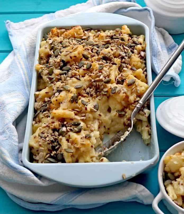 Roasted Cauliflower Mac and Cheese in blue pan with serving spoon and some missing