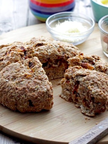 Sun-dried Tomato Cheddar Soda Bread with wedge cut out on cutting board