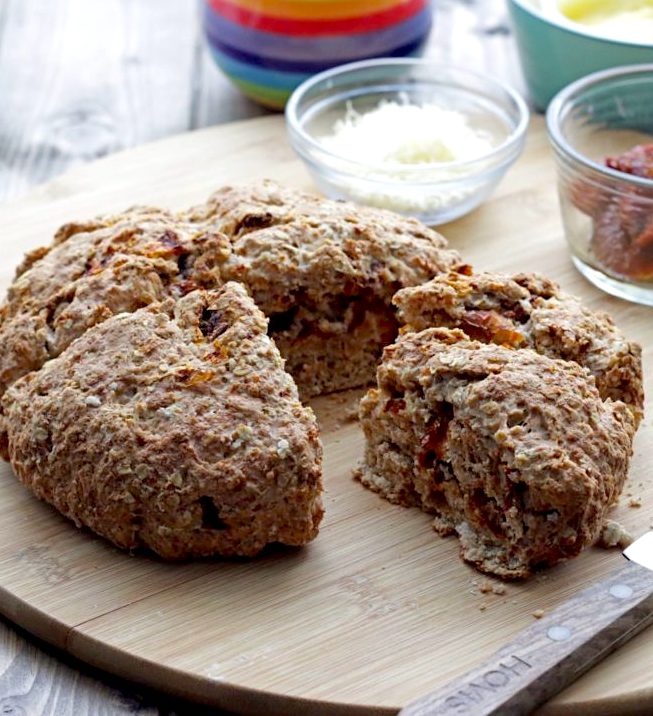 Sun-dried Tomato Cheddar Soda Bread with wedge cut out on cutting board