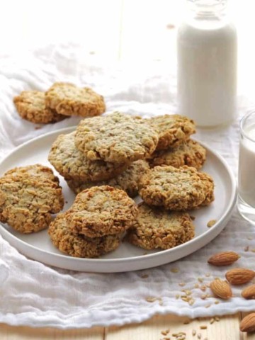 Vegan Almond Milk Flaxseed Oat Cookies on white plate with milk in bottle in background