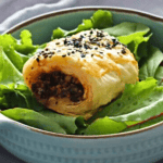Mushroom and Nut Vegetarian Sausage Roll on top of bowl of lettuce