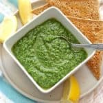 Parsley Pesto with Almonds in square white bowl with lemons and toast in background