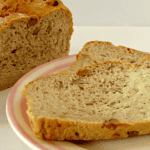 Walnut and Gruyere loaf with a buttered slice on a plate.