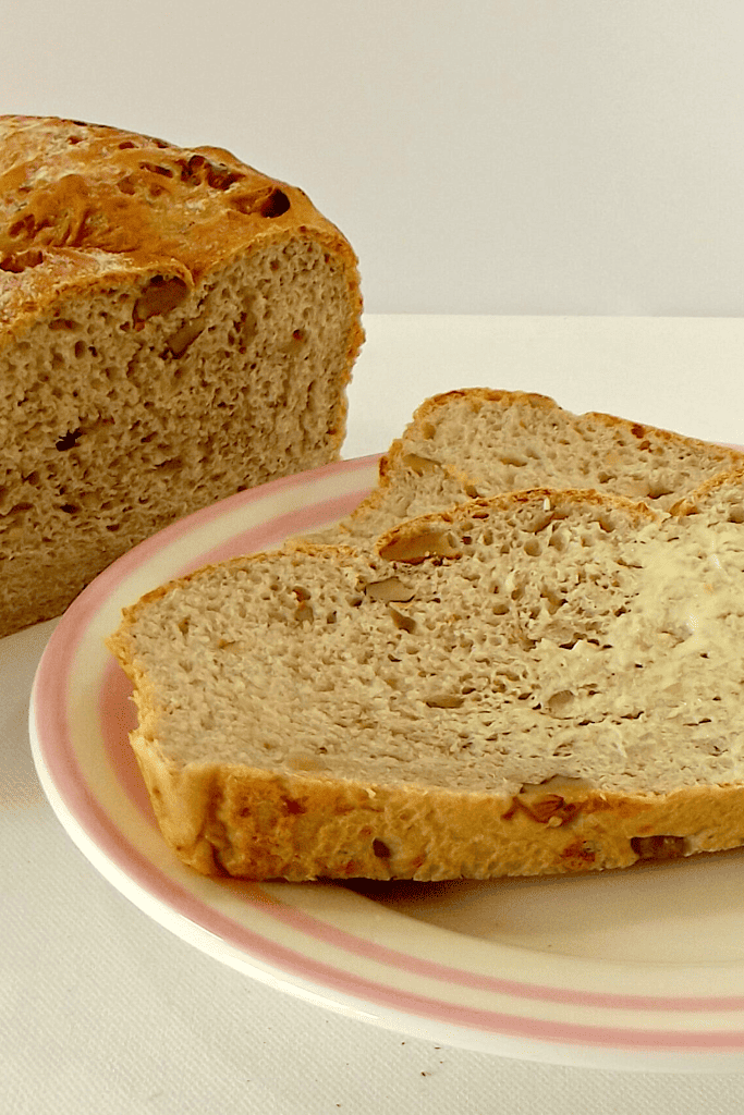 Walnut and Gruyere loaf with a buttered slice on a plate.