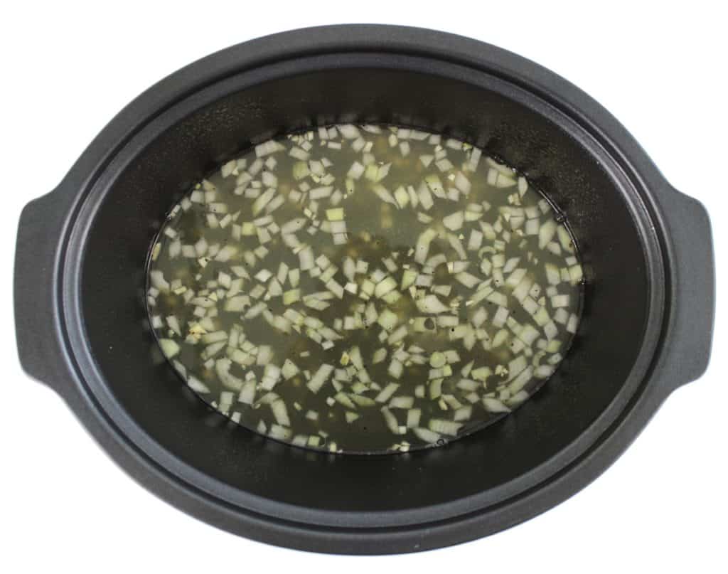chicken broth and chopped onion in cropckpot