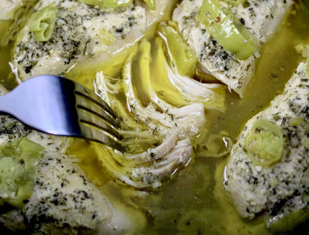 Mississippi chicken being shredded with fork in slow cooker