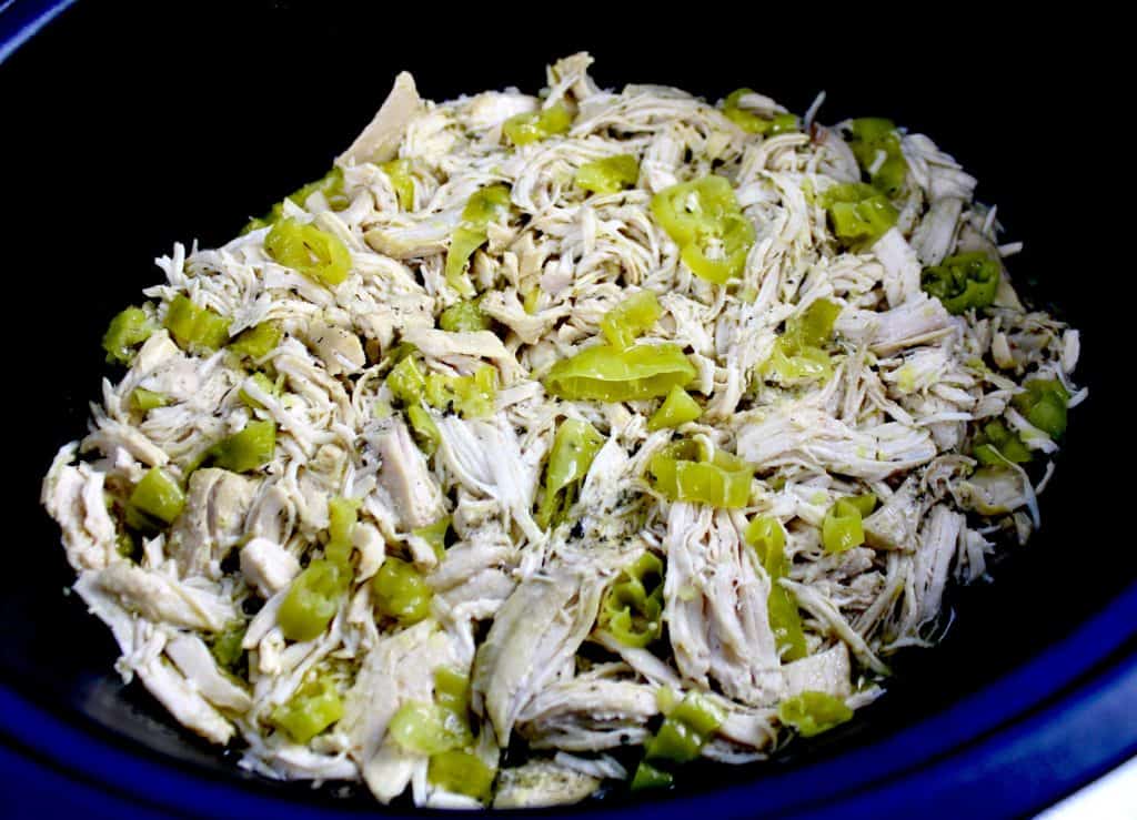Mississippi chicken shredded in slow cooker with sliced peppers