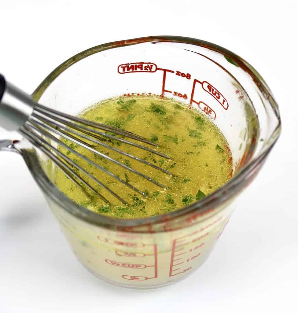 citrus dressing in glass cup with whisk