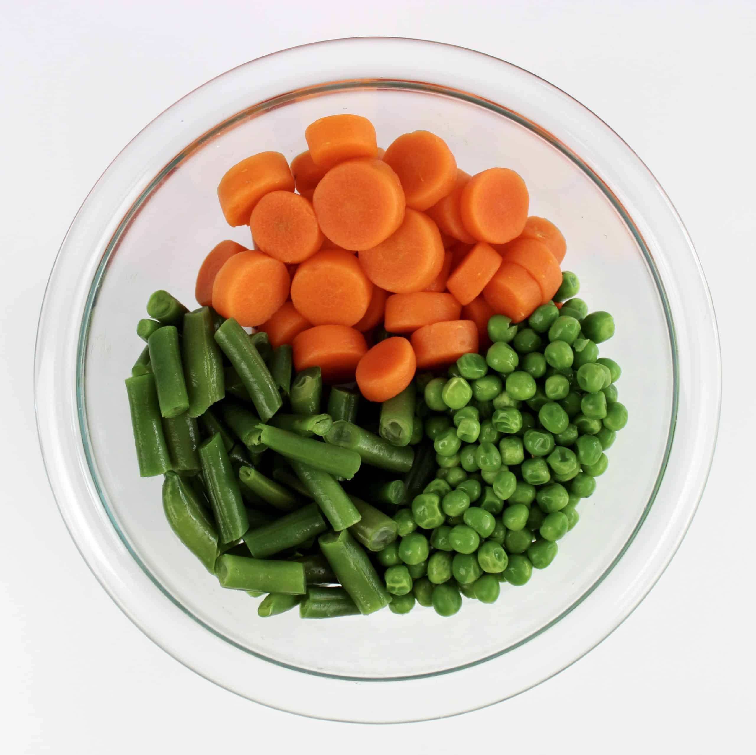 peas carrots green beans in glass bowl