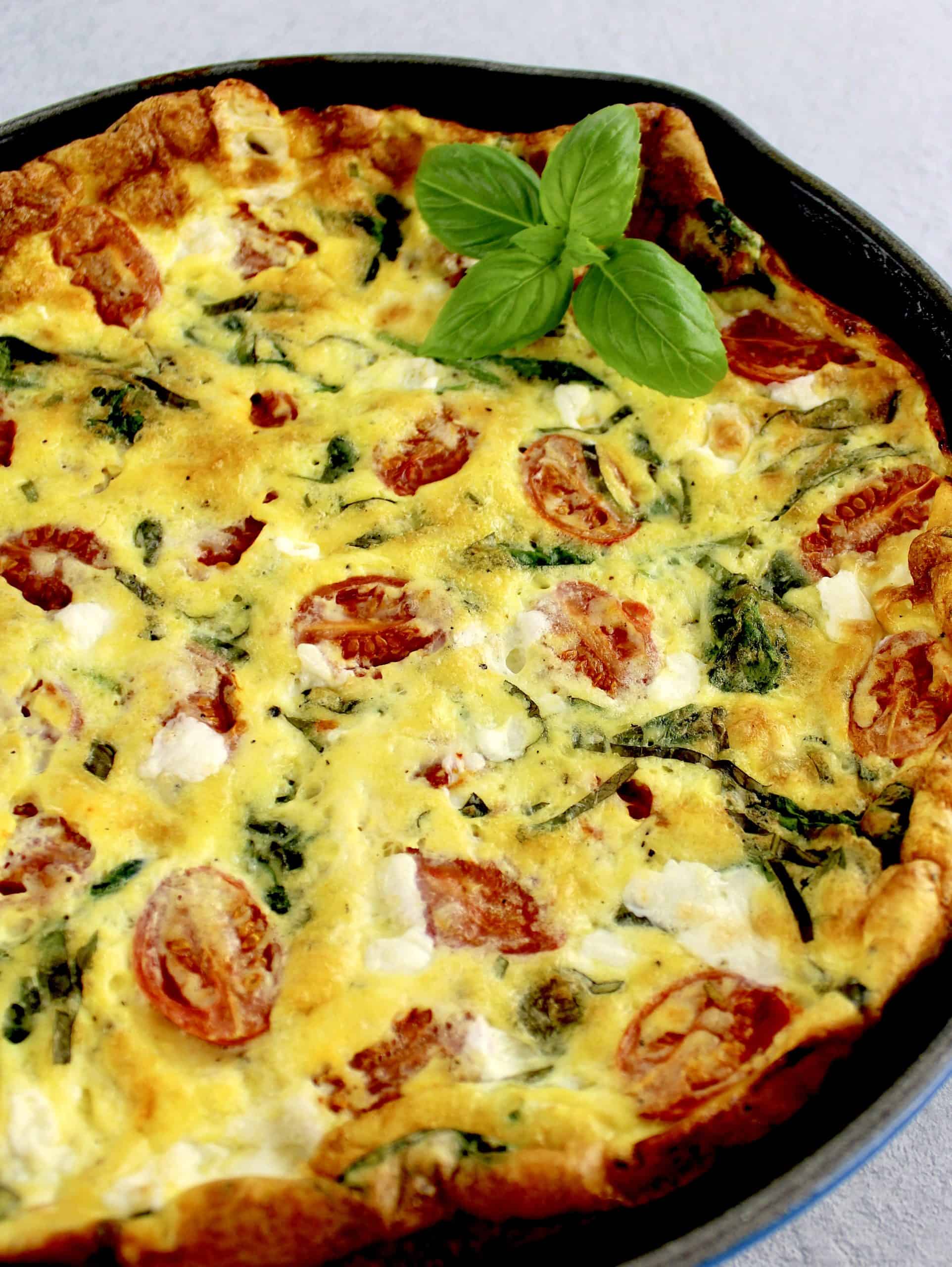 caprese frittata in skillet with basil garnish