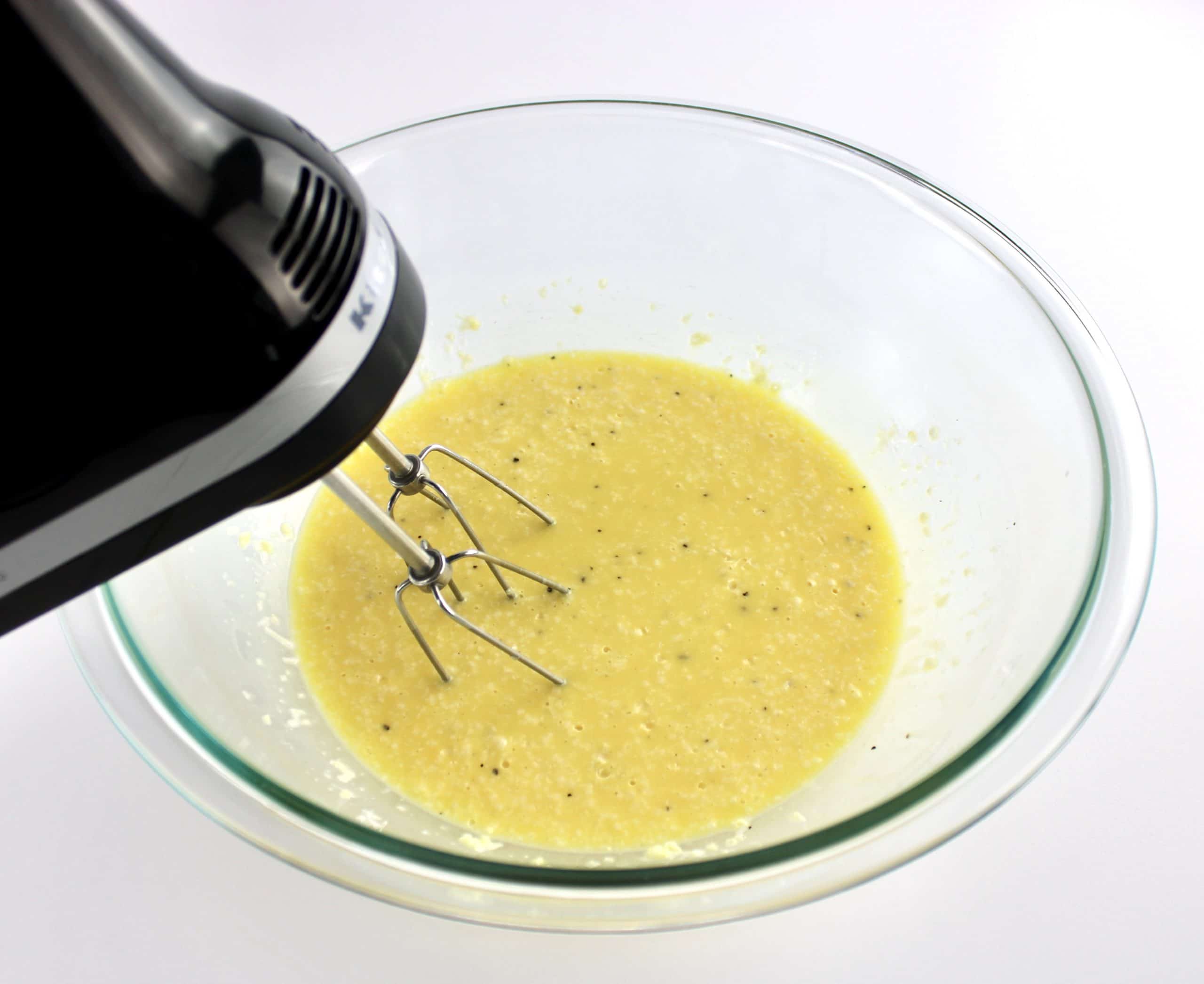 beaten eggs in glass bowl with hand mixer
