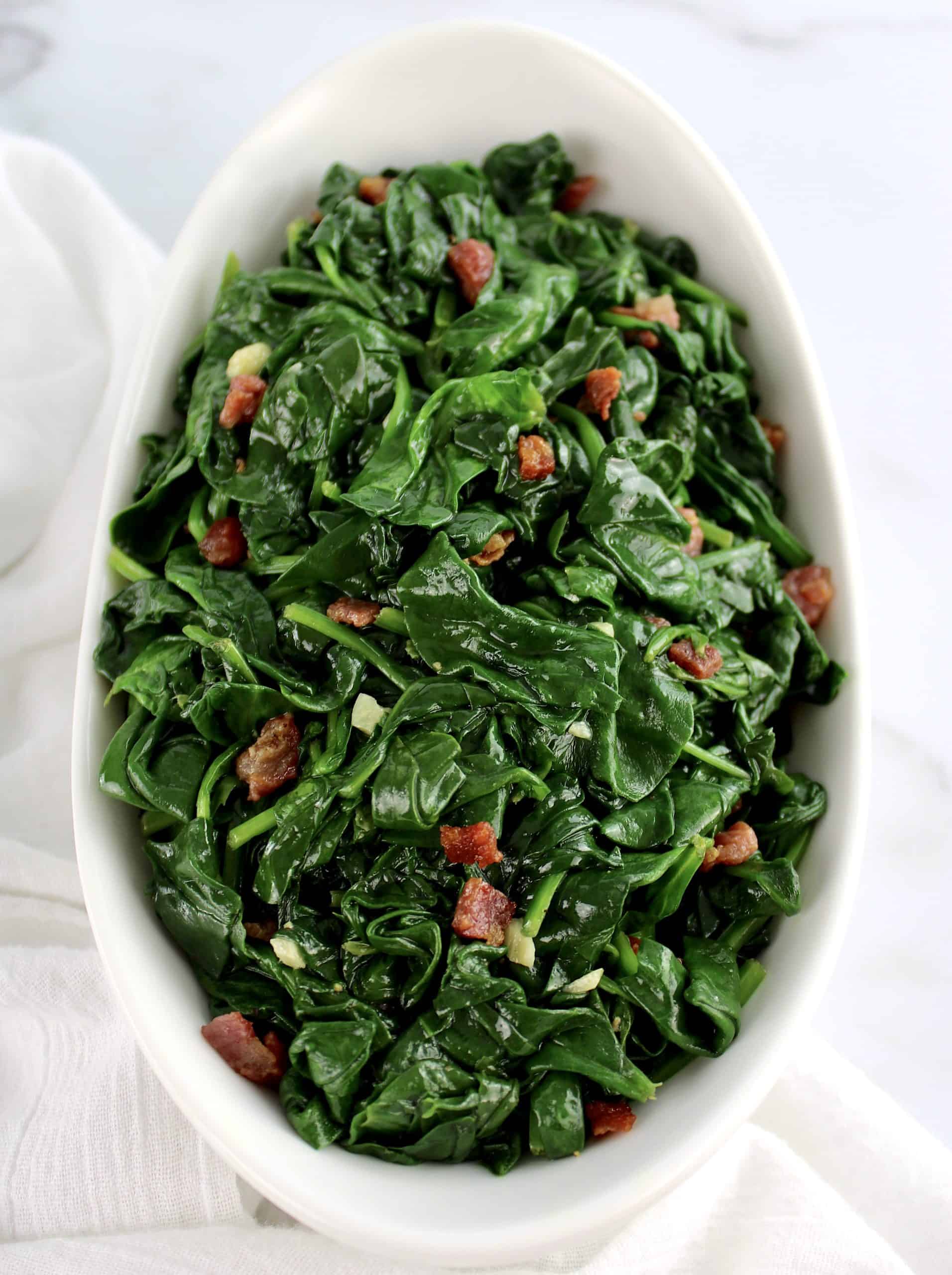 overhead view of Sautéed Spinach with Pancetta in white bowl