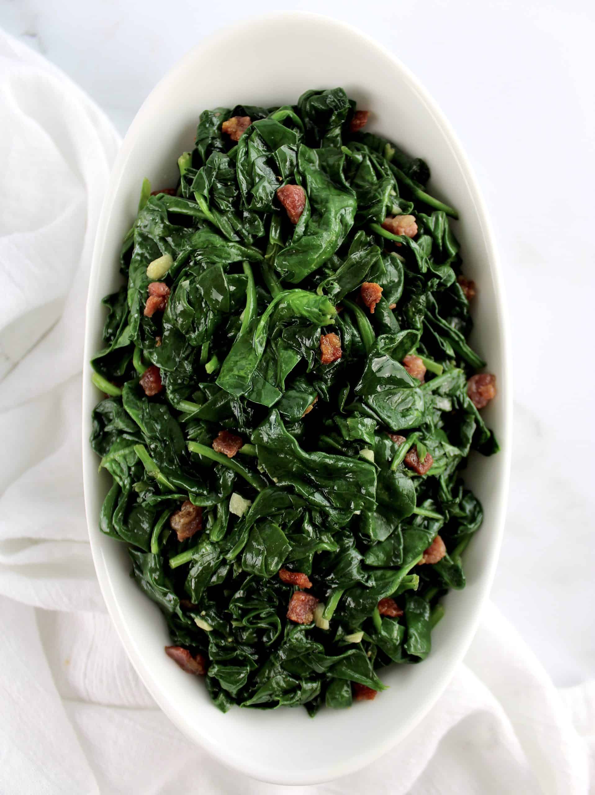 overhead view of Sautéed Spinach with Pancetta in white bowl