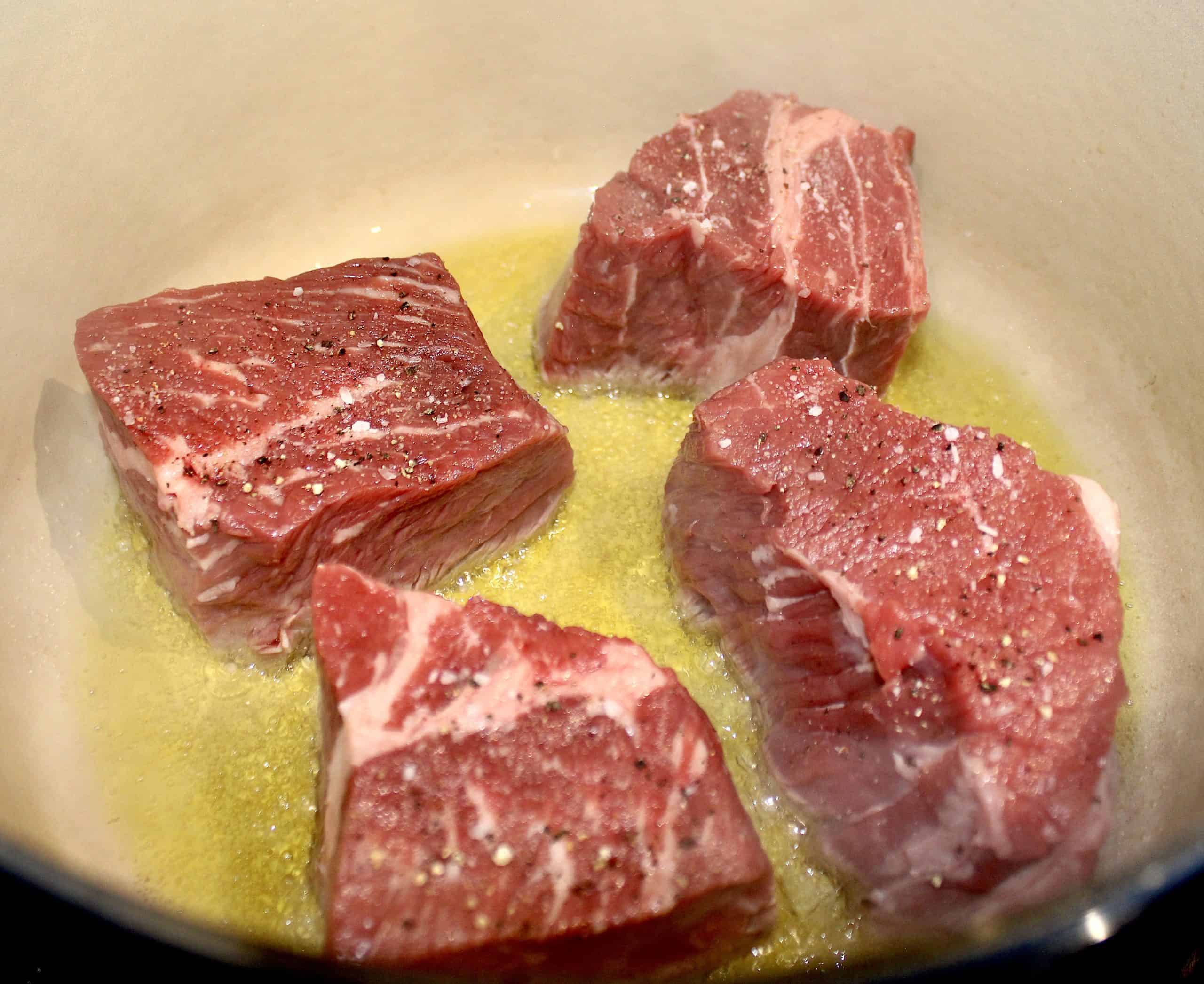 4 pieces of chuck roast searing in pan