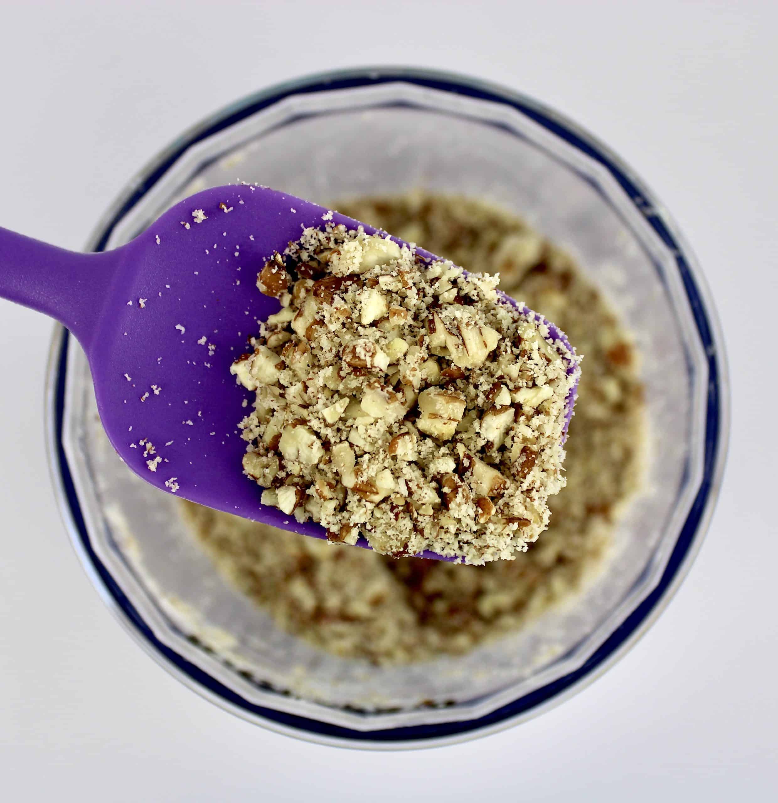 chopped pecans in purple spoon over mini chopper