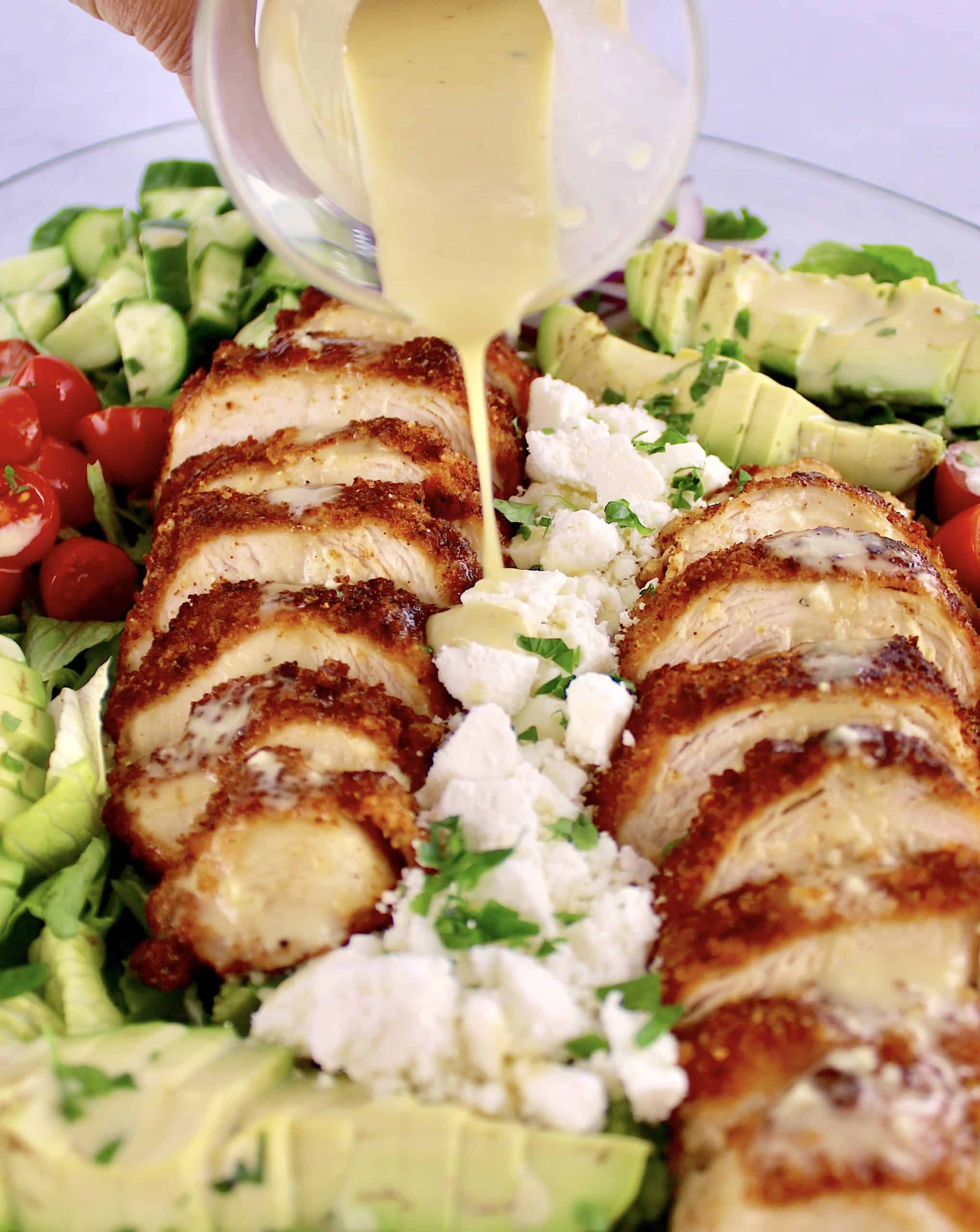 honey mustard dressing being poured over Crispy Chicken Salad 