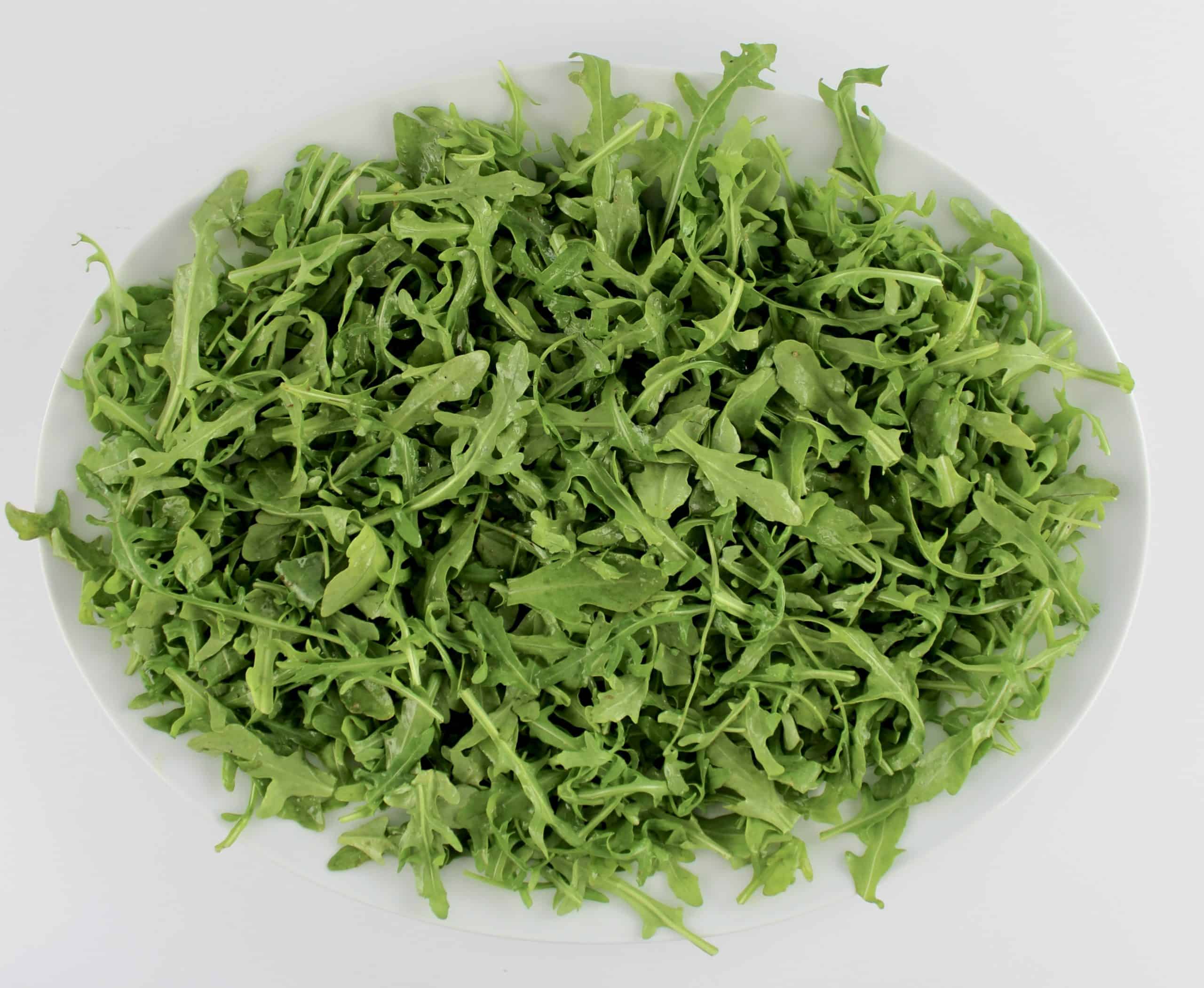 arugula with dressing on white platter