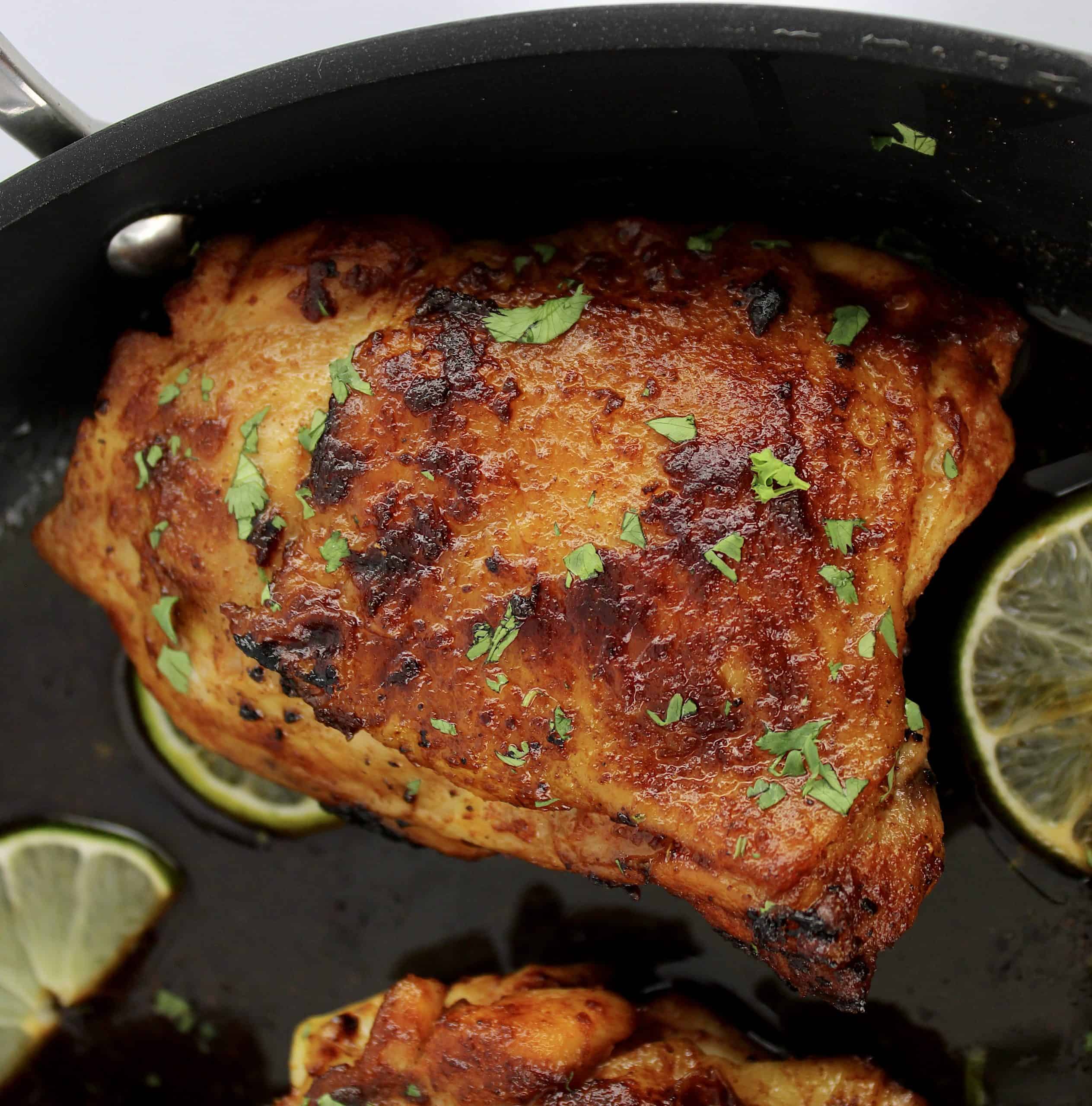 closeup of Paprika Chicken Thigh in skillet with lime half slices