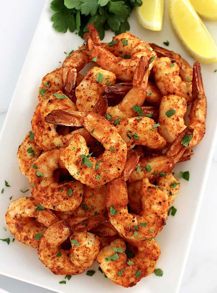 Air Fryer Frozen Shrimp on white plate with lemon and parsley on side