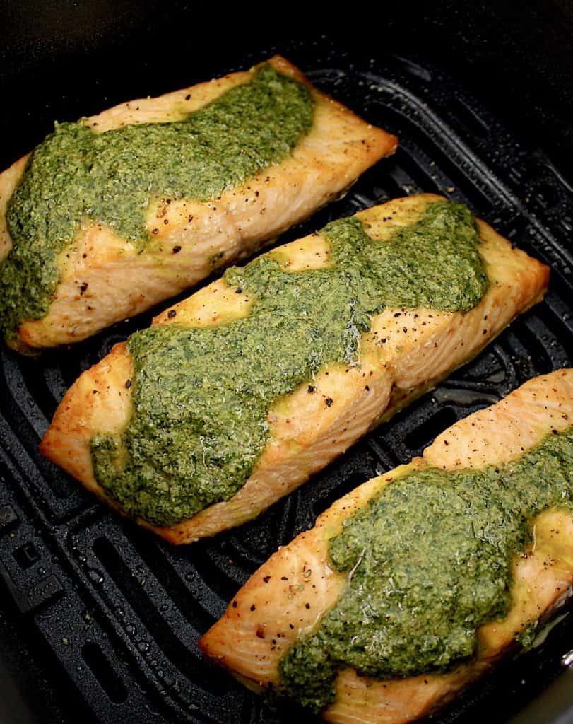 3 pieces of Air Fryer Pesto Salmon with pesto on top in air fryer basket