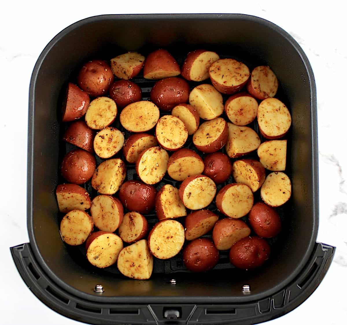 cut red potatoes in air fryer basket mixed with olive oil and spices