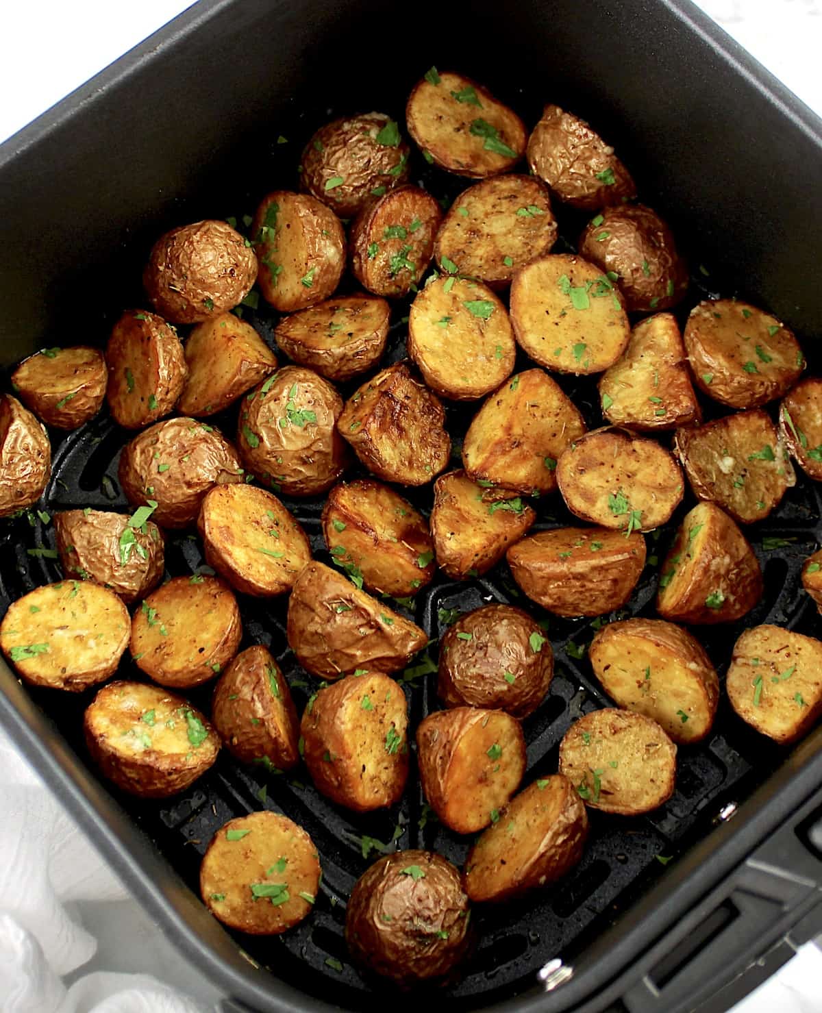 Air Fryer Red Potatoes in air fryer basket with chopped parsley 