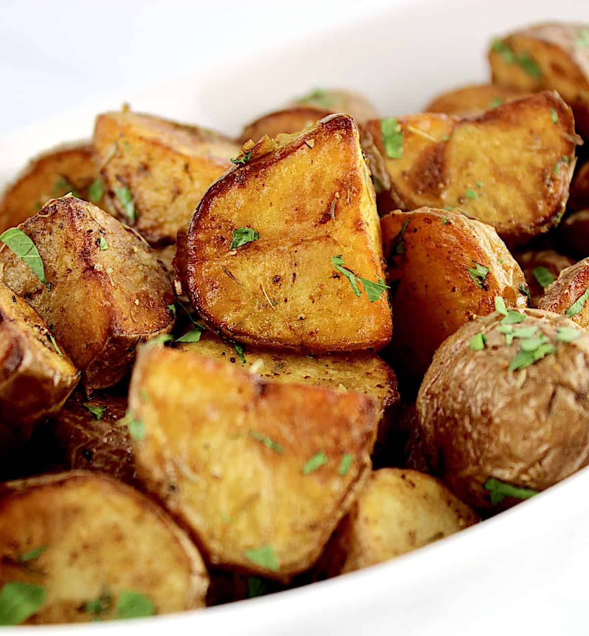 roasted potatoes inn white bowl with chopped parsley