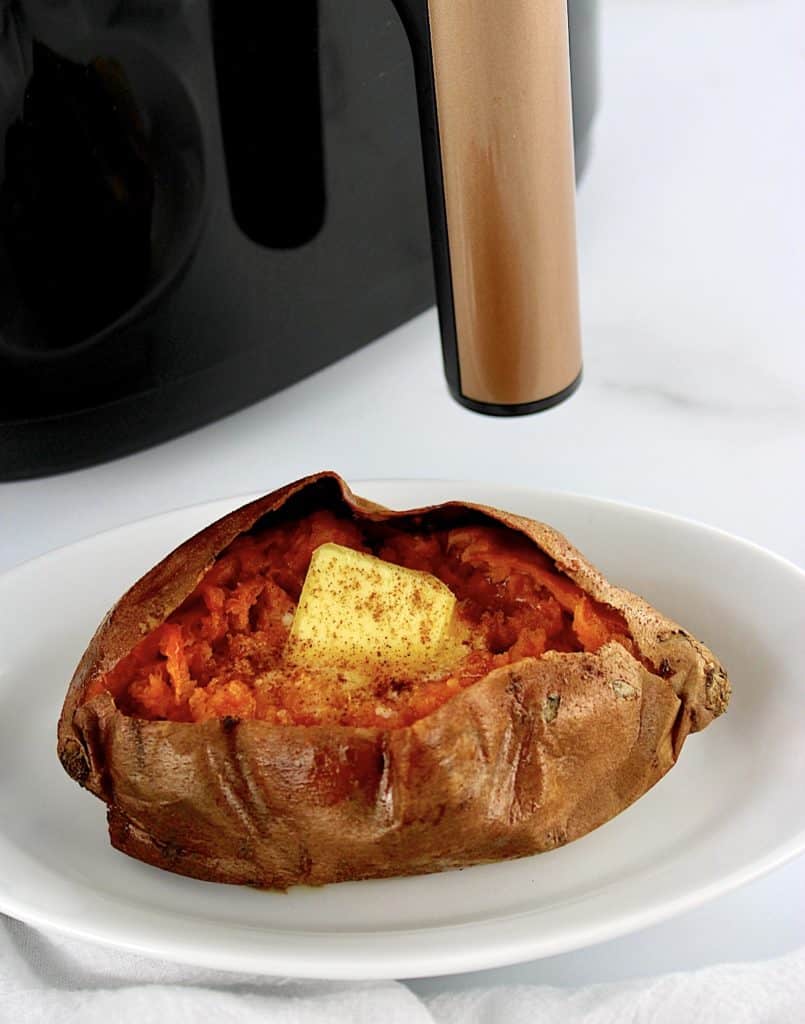 Air Fryer Sweet Potato on white oval plate with air fryer in background