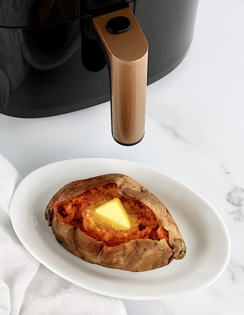 Air Fryer Sweet Potato on white oval plate with air fryer in background