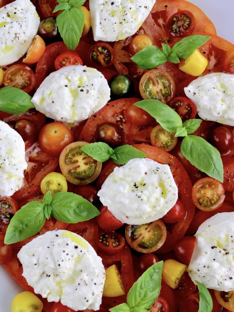 Burrata Caprese with olive oil drizzle and fresh basil leaves