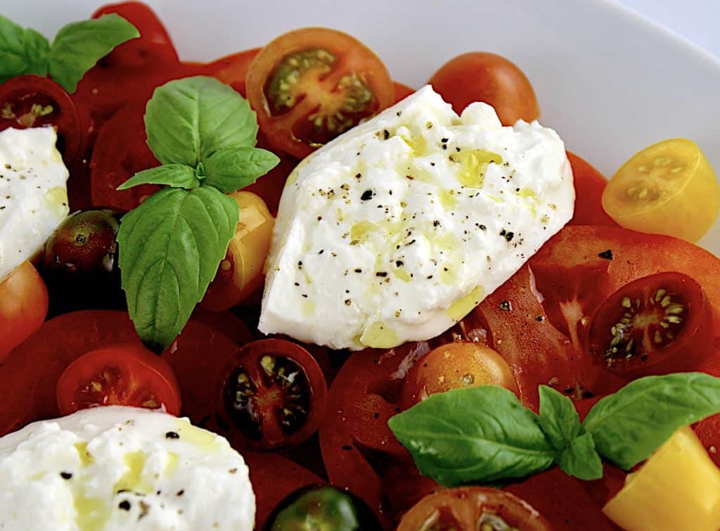 closeup of Burrata Caprese with olive oil drizzled over the cheese
