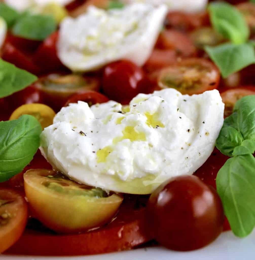 closeup of Burrata Caprese with olive oil drizzled over the cheese