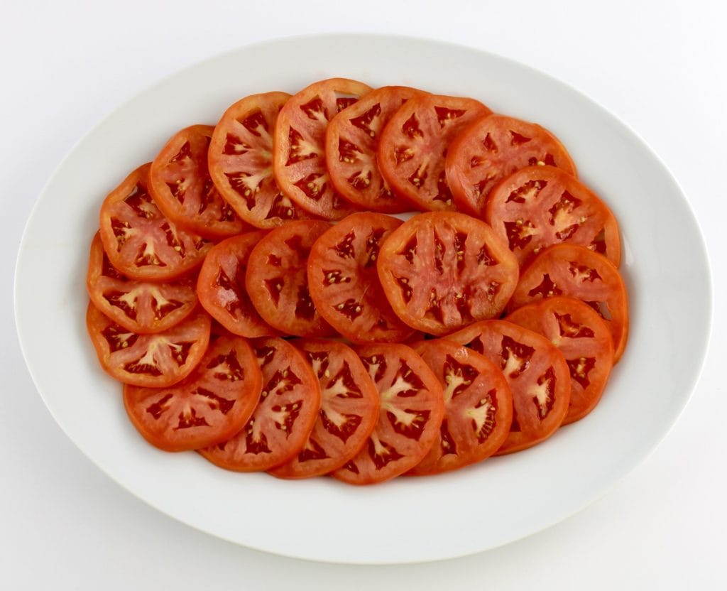 sliced tomatoes in concentric circle on white oval platter