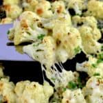 Cheesy Roasted Cauliflower being lifted off sheet pan with silver spatula