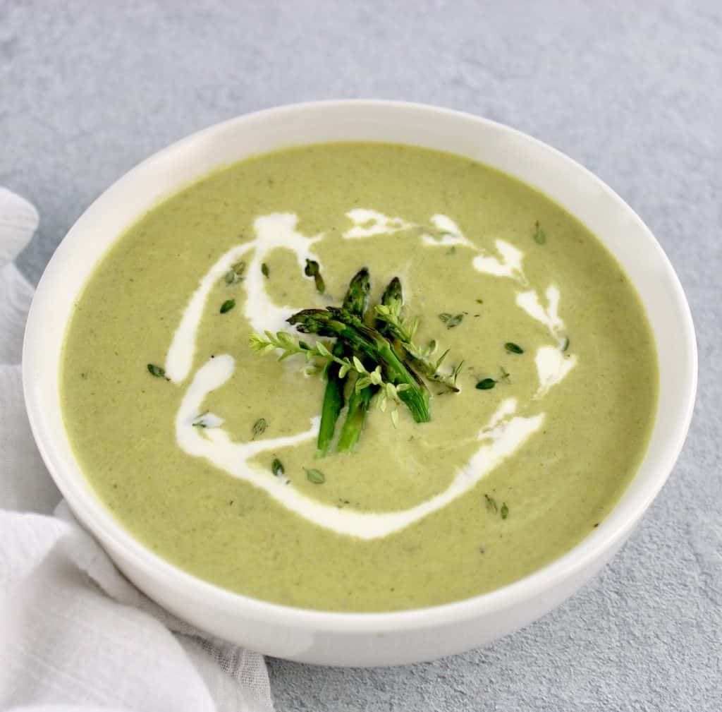Cream of Asparagus Soup with splash of cream and asparagus tips garnish on top
