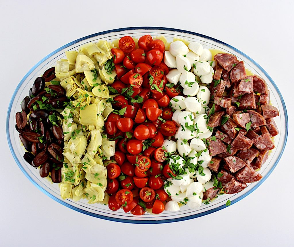 chopped olives tomatoes mozzarella salami and artichoke hearts in oval glass bowl