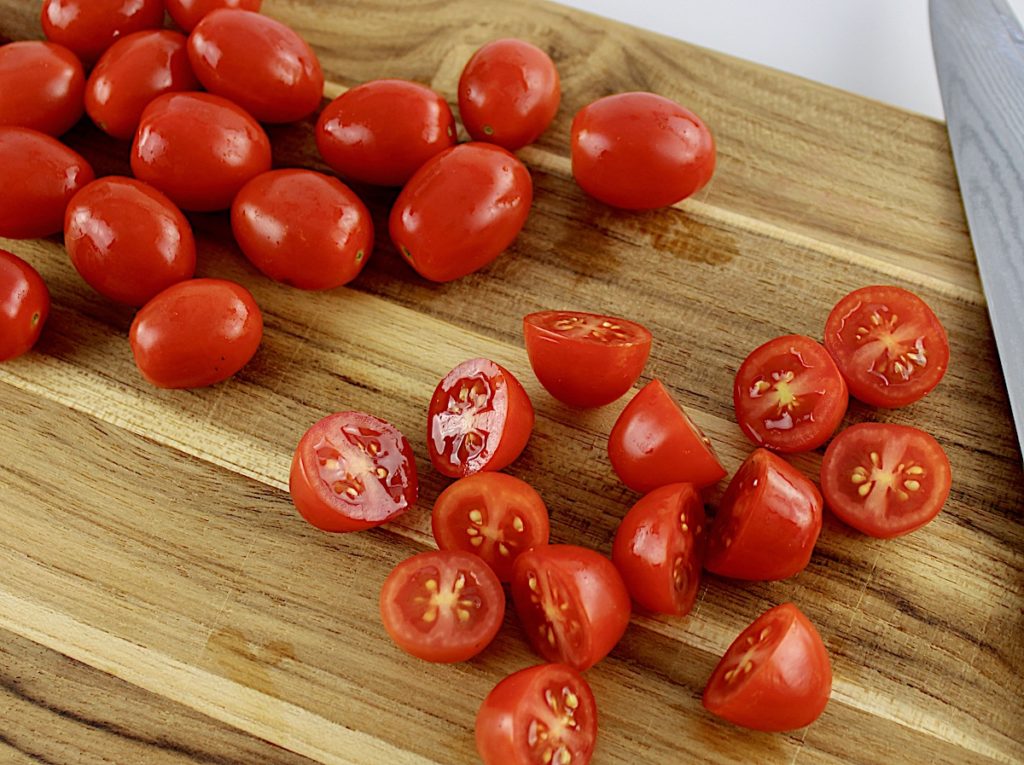 cherry tomatoes cut in half on cutting board