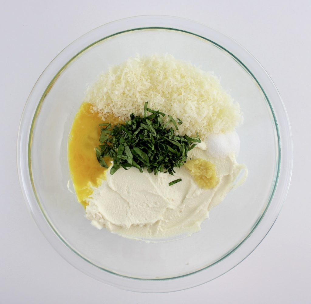 ricotta cheese parmesan grated garlic egg and chopped basil in glass bowl