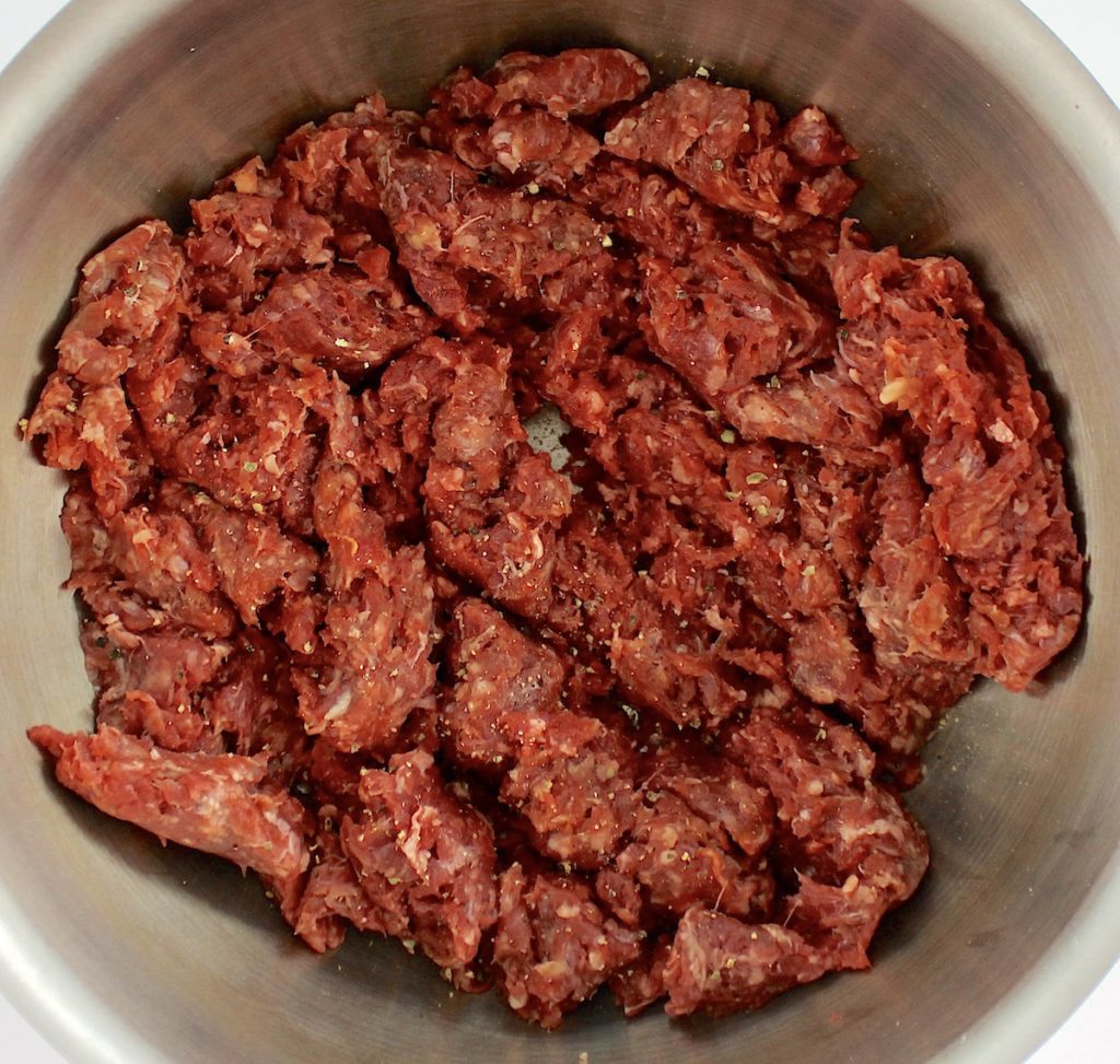raw ground beef in saucepan with salt and pepper